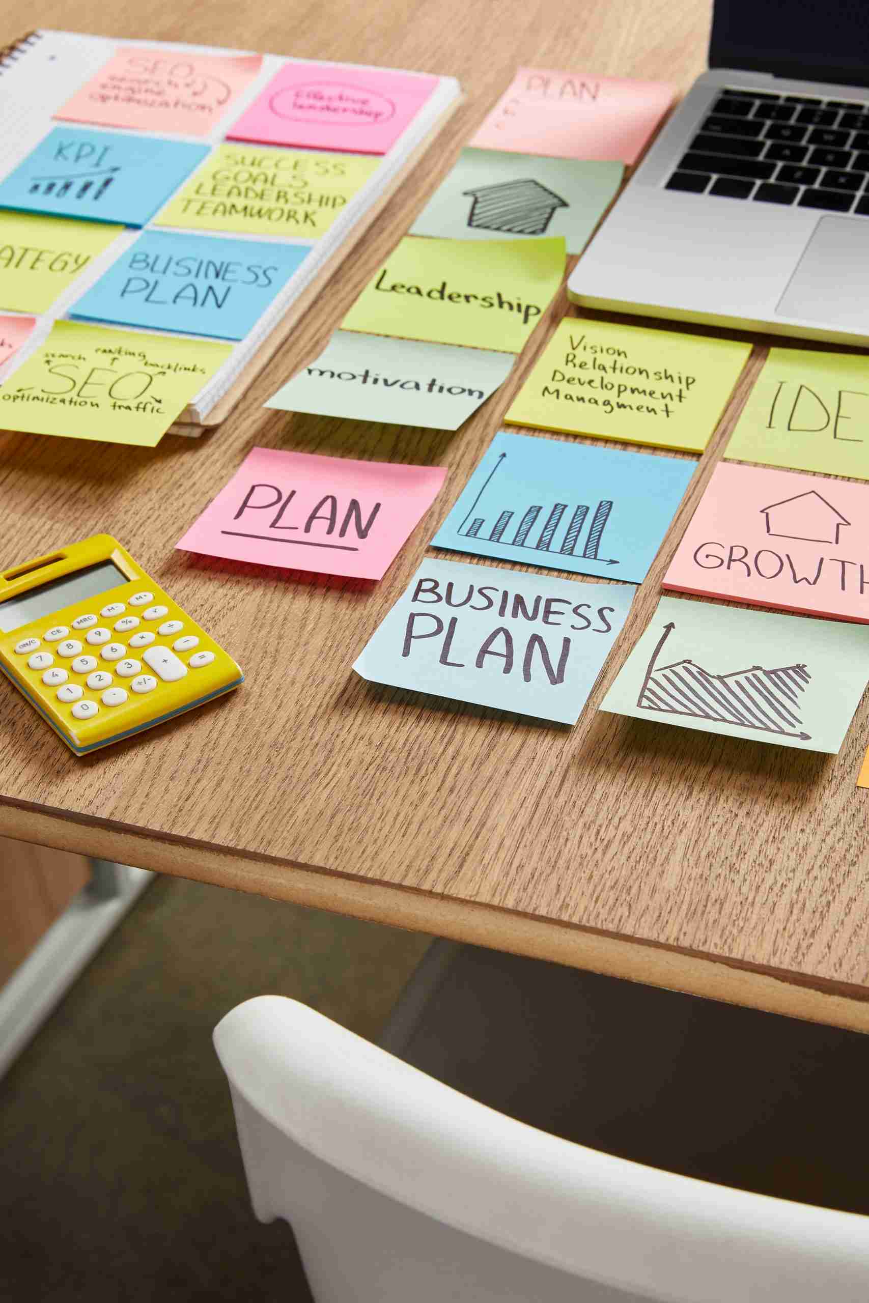 A desk with sticky notes, a calculator and a laptop. A desk with sticky notes, a calculator and a laptop.